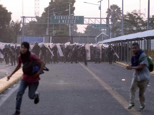 Central American migrants run from Mexican authorities during clashes on a border bridge that connects Guatemala and Mexico, in Tecun Uman, Guatemala, Sunday, Oct. 28, 2018. A new group of migrants, who called themselves a second caravan, gathered on a bridge after forcing their way through a gate at the Guatemalan end. (AP Photo/Santiago Billy)