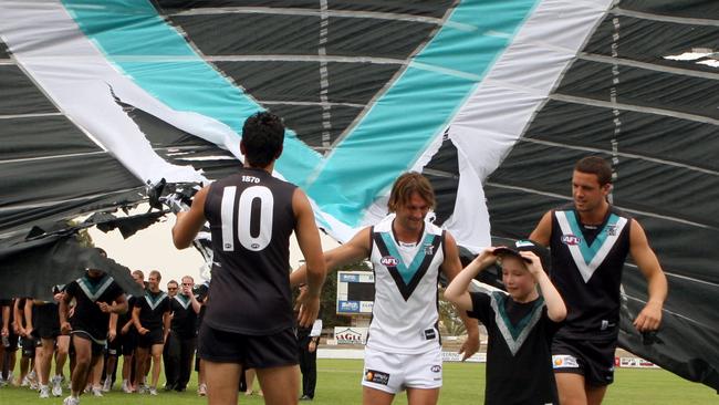 Jumper designer Lucy Burford leads Port Adelaide Power footballers Travis Boak and Domenic Cassisi wearing new team home strip, with footballer Jacob Surjan wearing away guernsey, in 2010.