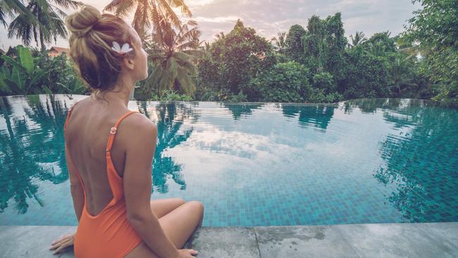 Young woman standing on the edge of an infinity pool, Ubud, Bali People travel vacations concept.