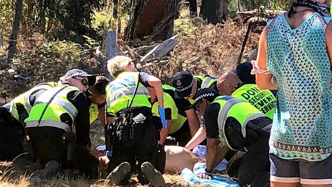 Emergency services attend to a man before he is loaded into an ambulance at Rainbow Serpent Festival.