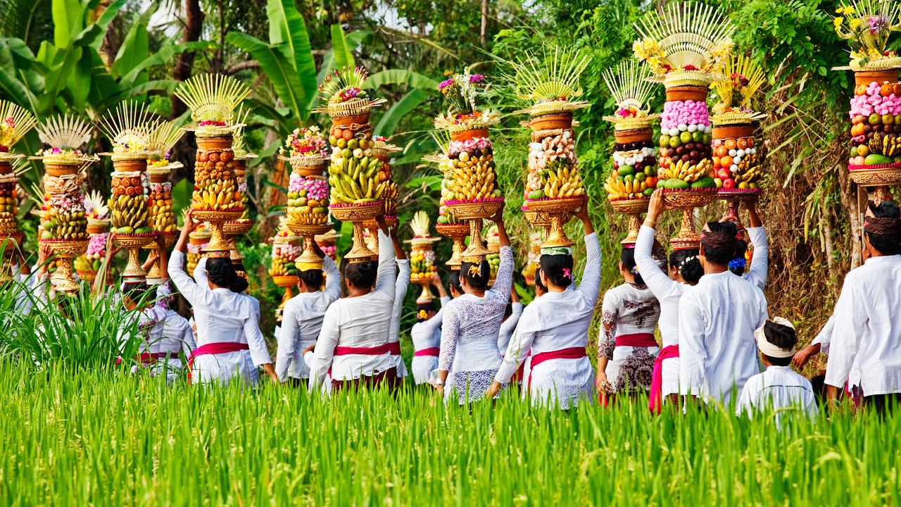 There is another type of offering called Banten Tegeh where Balinese women carry a stack of food and fruits on their head while walking towards a temple. Picture: Getty