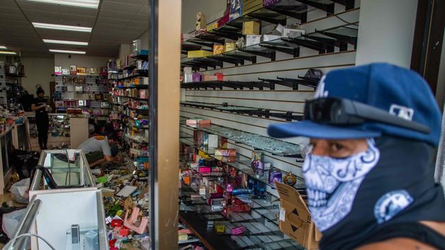 A man wearing a face cover looks at a looted store in Downtown Long Beach, California. Looting in parts of San Francisco, Chicago, Portland and Los Angeles are chilling proof of what happens when crime isn’t prosecuted. Picture: Apu Gomes/AFP