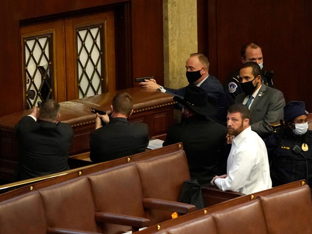 U.S. Capitol police officers point their guns at a door that was vandalised in the House Chamber during a joint session of Congress. Picture: AFP