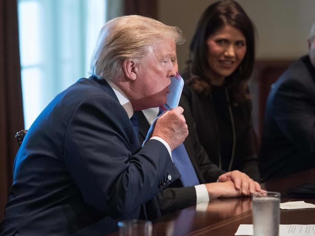US President Donald Trump kisses a sample of the proposed new tax form as he meets with House Republican leaders and Republican members of the House Ways and Means Committee at the White House in Washington, DC, on November 2, 2017. / AFP PHOTO / NICHOLAS KAMM