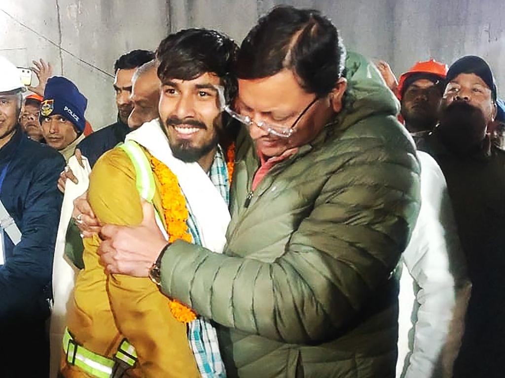 This handout picture released by Uttarakhand's Department of Information and Public Relation (DIPR) and taken on November 28, 2023 shows Chief minister of Uttarakhand Pushkar Singh Dhami (R) embracing a contruction worker following his rescue from inside the under construction Silkyara tunnel during a rescue operation for trapped workers after a section of the tunnel collapsed in the Uttarkashi district of India's Uttarakhand state. Indian rescuers on November 28 began bringing out the first of the 41 men trapped for 17 days behind tonnes of earth inside a Himalayan road tunnel after a marathon engineering operation to free them. (Photo by Department of Information and Public Relation (DIPR) Uttarakhand / AFP) / RESTRICTED TO EDITORIAL USE - MANDATORY CREDIT "AFP PHOTO /  Department of Information and Public Relation (DIPR) Uttarakhand " - NO MARKETING NO ADVERTISING CAMPAIGNS - DISTRIBUTED AS A SERVICE TO CLIENTS