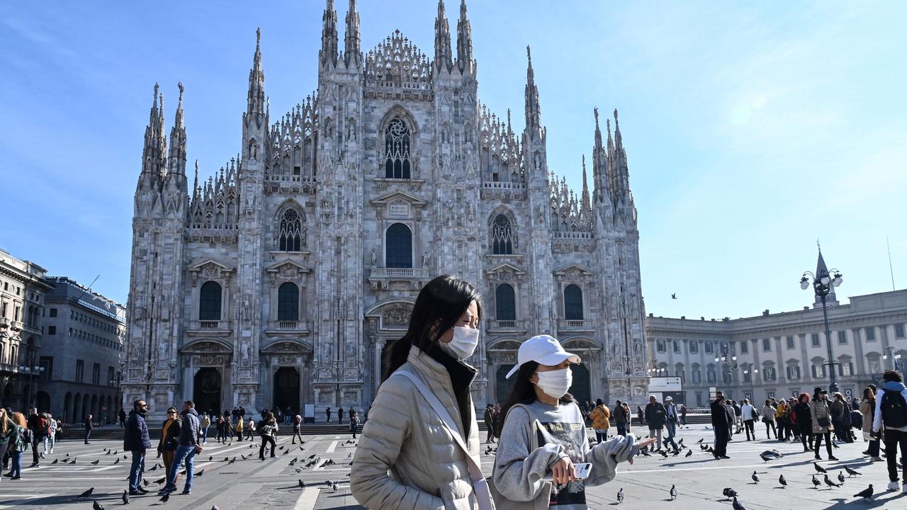 Two women wearing protective face masks walk across the Piazza del Duomo, in front of the Duomo, in central Milan. Picture: AFP/ANDREAS SOLARO