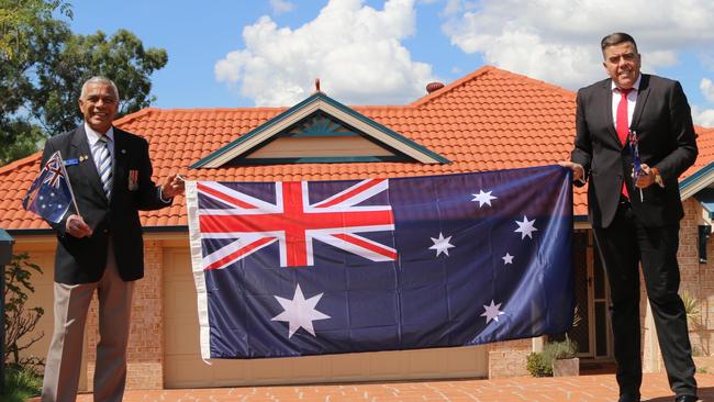 Centenary Suburbs RSL Sub Branch president Georges Lefevre and Federal MP Milton Dick with the Aussie flags available for residents on Anzac Day.