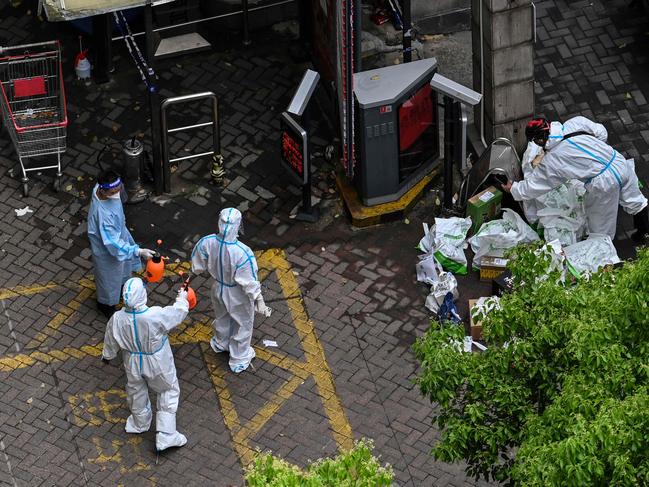 Workers wearing personal protective equipment (PPE) spray disinfectant on a colleague during the Covid-19 lockdown in the Jing'an district in Shanghai. Picture: AFP