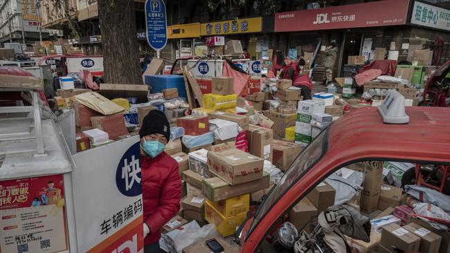 A delivery driver organises packages in the street that are part of a backlog due to Covid outbreaks outside a depot in Beijing, China. Picture: Kevin Frayer/Getty Images