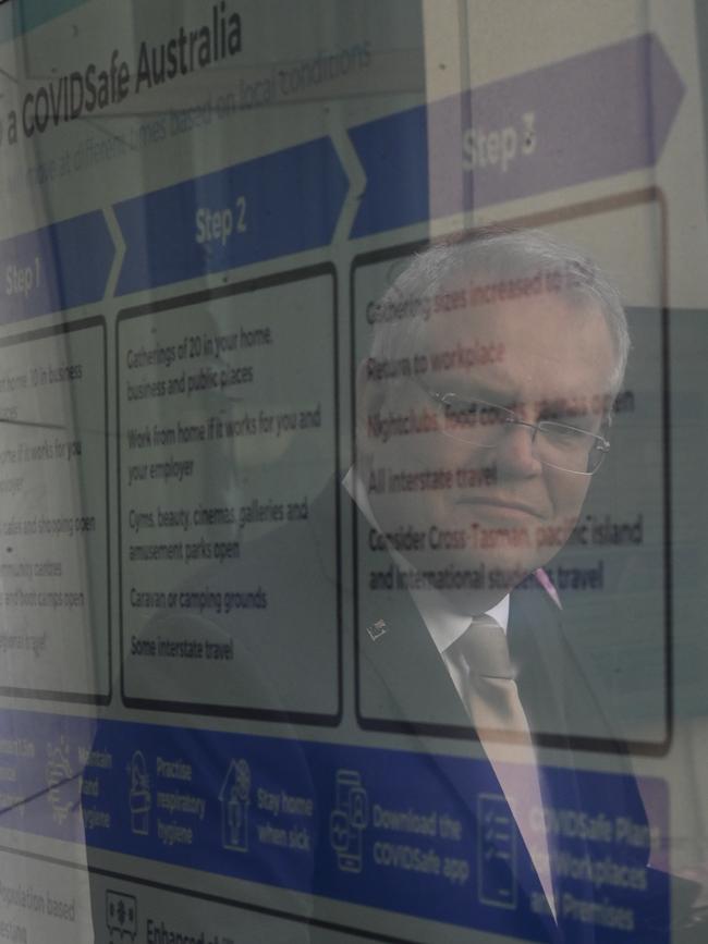 Scott Morrison is seen in a reflection on a graphic showing the government’s plan for recovery from coronavirus restrictions. Picture: AAP