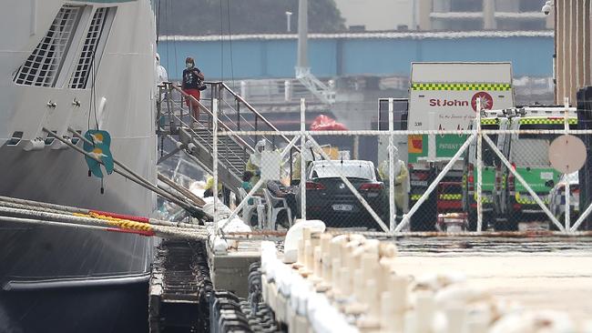 A passenger walks from the MV Artania to be attended to by waiting paramedics on the wharf at the Fremantle Passenger Terminal.