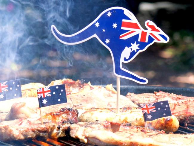 Iconic Australian BBQ close up of man cooking chops, sausgaes and steak, outdoors in garden setting.