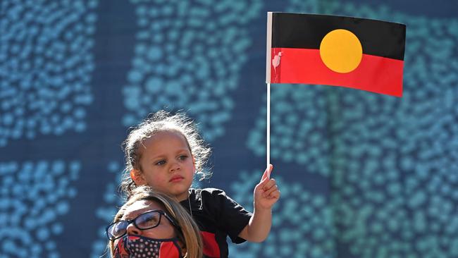 A young girl holds up an Australian Aboriginal flag. Picture: AFP