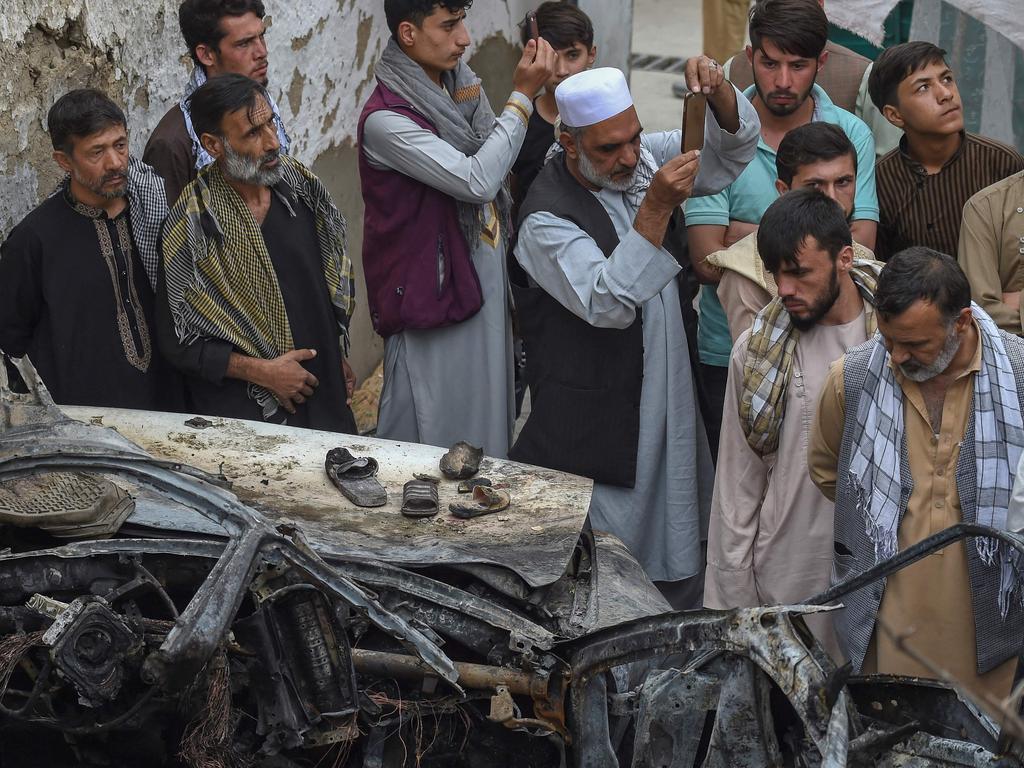 Afghan residents and family members of the victims gather next to a damaged vehicle after a US drone air strike in Kabul. Picture: AFP