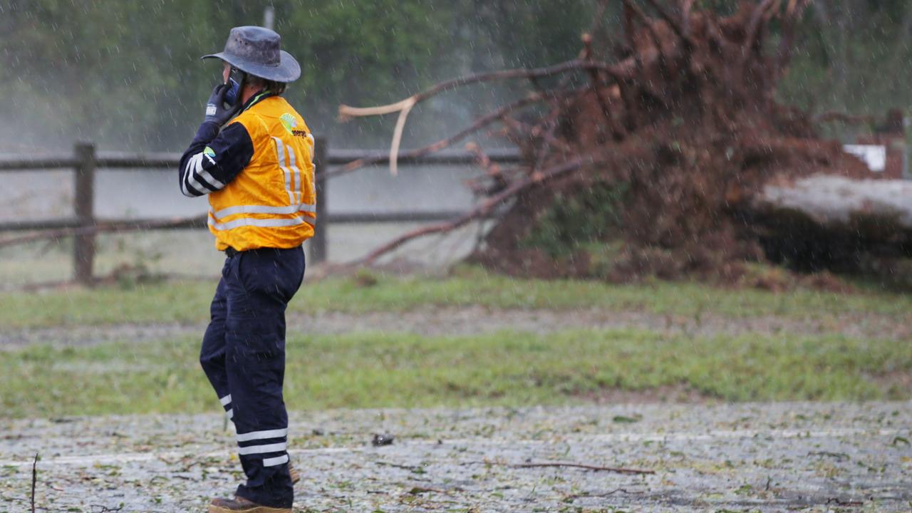 Energex workers tend to fallen trees across a road after a super cell storm tore through Long Flat south of Gympie. Photo Lachie Millard