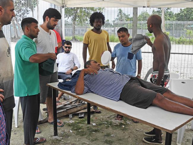 Asylum seekers in the Lombrum detention centre abandoned by Australia care for very sick Rohingya refugee Salim Kwawning. Salim suffers frequent fits and has been sick for four years. Picture: Brian Cassey