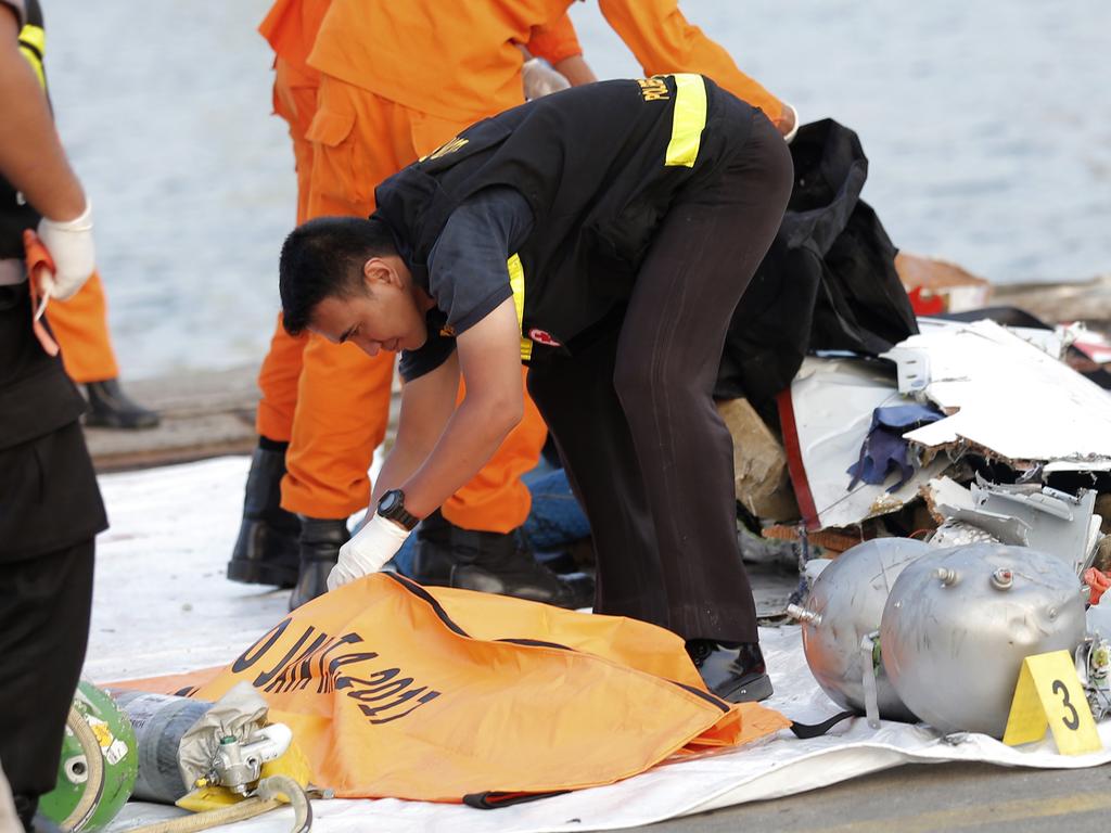 A member of police forensic team examines the remains recovered from the area where the Lion Air flight crashed, killing all 189 passengers. Picture: AP