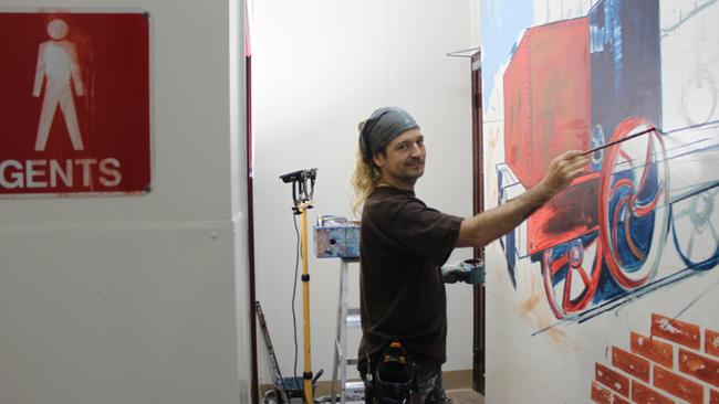 With a few dabs of paint, Akos Juhasz starts work on one of the walls in the men's toilet