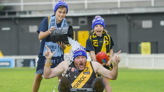 Andrew ‘Cosi’ Costello with Glenelg primary school kids, Jude, 11, and Lani, 10, at Glenelg Oval for MND charity event. Picture: Roy VanDerVegt