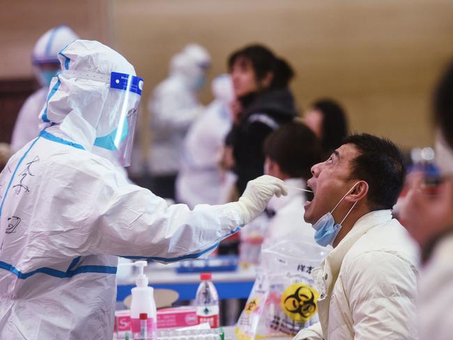 A medical worker (L) takes a swab sample from a service worker to be tested for coronavirus in Hangzhou in China's eastern Zhejiang province. Picture: AFP / China OUT