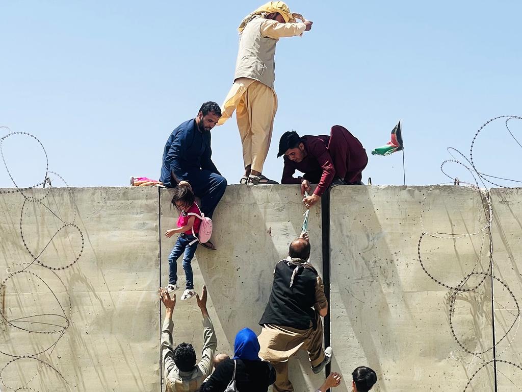 Families scale the wall to Hamid Karzai International Airport as they try to flee Kabul. Picture: Haroon Sabawoon/Anadolu Agency via Getty Images