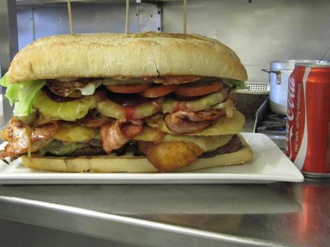 The Coke can beside this burger shows how big it is — it certainly lives up to its name as the Triple Bypass Burger. Source: www.donnybrookhotel.com.au