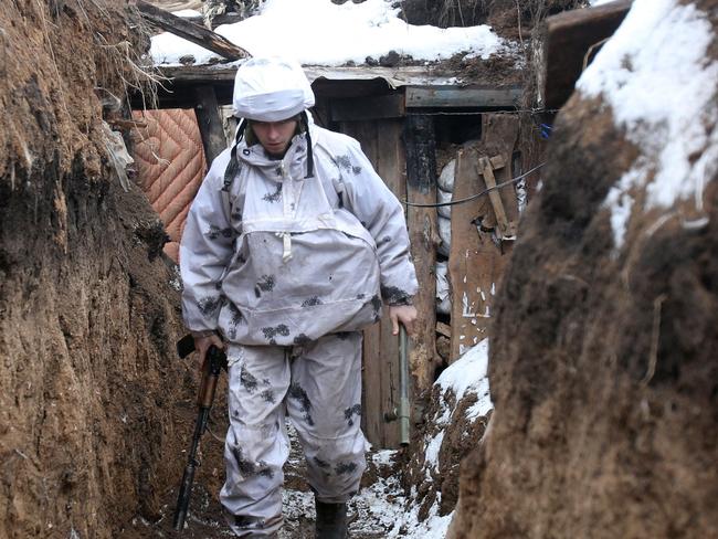 TOPSHOT - An Ukrainian serviceman walks along a snow covered trench on the frontline with the Russia-backed separatists near Verkhnetoretskoye village, in the Donetsk region on February 1, 2022. (Photo by Anatolii STEPANOV / AFP)