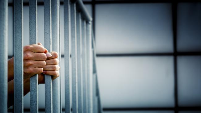 Generic photo of hands in jail cell.