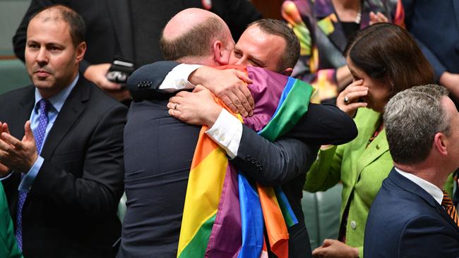 Josh Frydenberg, Trent Zimmerman and Tim Wilson (embracing) celebrate the passing of the Marriage Amendment Bill in the House of Representatives in December 2017.