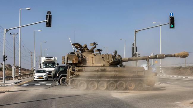 An Israeli army self-propelled howitzer moves past waiting traffic while crossing a road along the border with the Gaza Strip this week. Picture: AFP