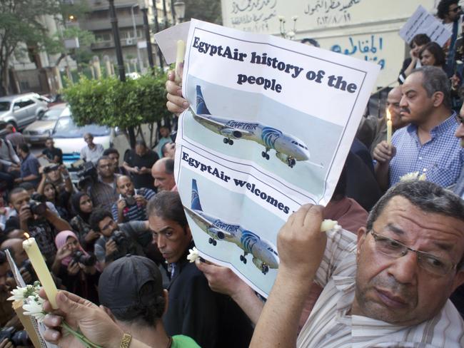 An Egyptian journalist holds a candle and a poster supporting EgyptAir during a candlelight vigil for the victims of the plane disaster. Picture: AP Photo/Amr Nabil