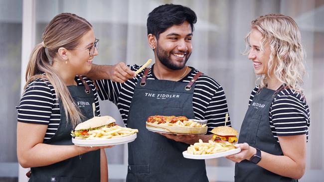 Food and beverage staff, from left, Phoebe Copland, Krishay Kumar and Tamsin Buchananat from The Fiddler in Rouse Hill serve up some pub lunches with fries. Picture: Sam Ruttyn