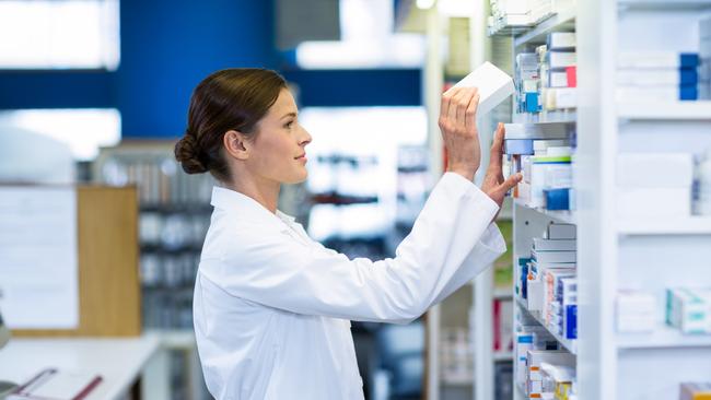 A pharmacist checks medicine on a shelf at a pharmacy. Generic image