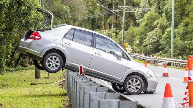 A woman was rescued from this car, now stuck on a guard rail after flooding through Springacre Road, Thornlands on Monday. Picture: Richard Walker.