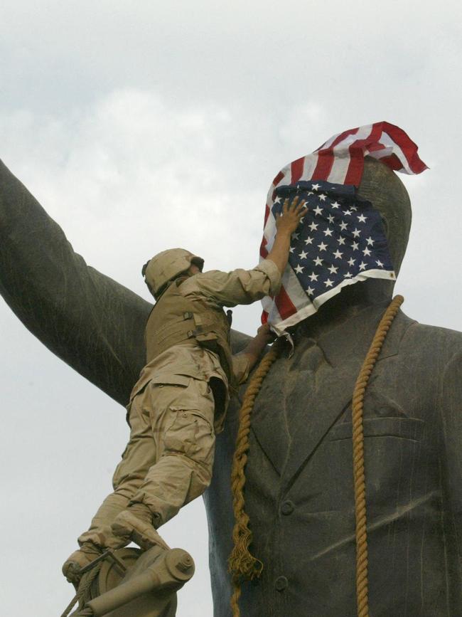 A US Marine covers the face of Iraqi President Saddam Hussein's statue with the US flag after the dictator was toppled. Picture: AFP.