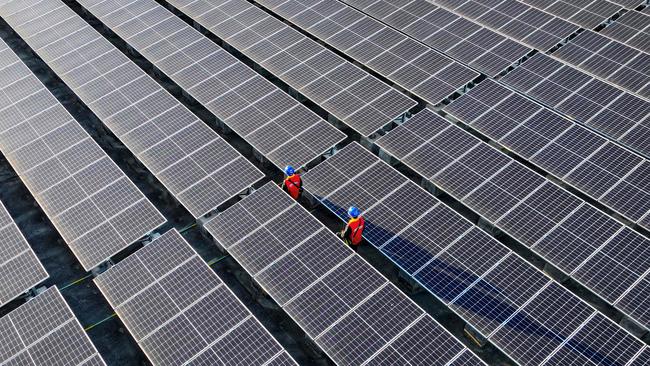 TOPSHOT - This photo taken on February 21, 2024 shows workers inspecting solar panels at a rooftop of a power plant in Fuzhou, in southern China's Fujian province. (Photo by AFP) / China OUT