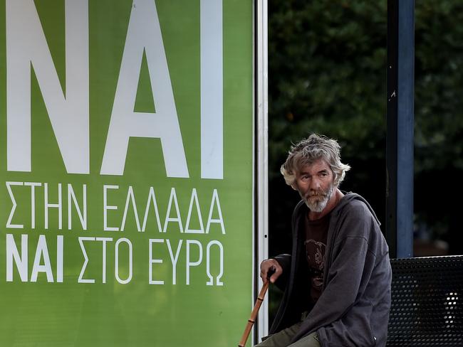 Home of democracy ... A man sits at a bus station next to a poster reading "YES to Greece, yes to the euro". Picture: Aris Messinis/AFP