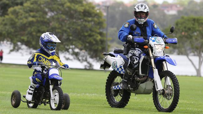 Honorary officer Finn O'Donovan rides alongside a highway patrolman at during his special day at a Rozelle park in. Picture: John Feder