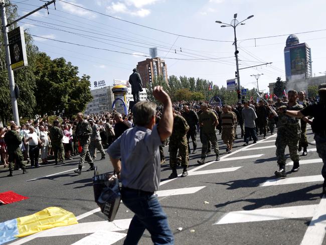 A man throws a projectile and people watch as captured Ukrainian soldiers walk on Lenin square in Donetsk, eastern Ukraine, during a parade in mockery of the country's Independence Day celebrations. Picture: Max Vetrov