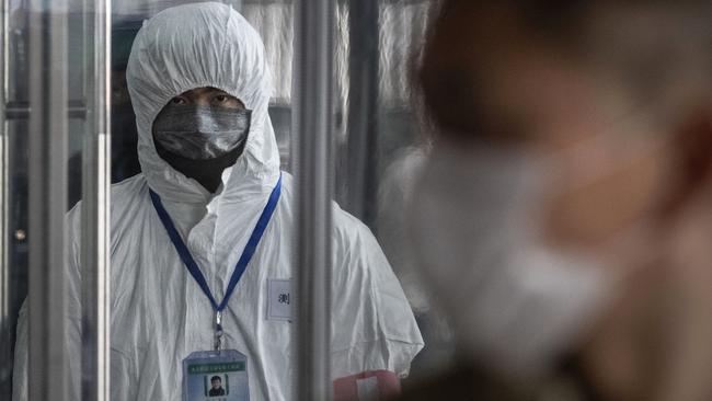 A Chinese health worker waits to check the temperature of travellers entering a Beijing train station. Picture: Kevin Frayer/Getty Images