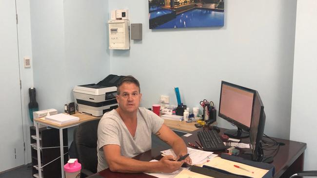 Builder Adrian Hill was photographed working in an office in Broadbeach displaying his construction company's signage despite him ann the company being unlicensed. Photo: Supplied