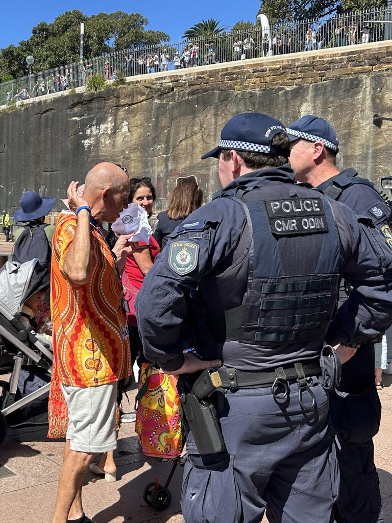 A man wearing an Aboriginal print shirt and carrying an Aboriginal flag was blocked from approaching the Opera House by several police officers. Picture: Adelaide Lang / NewsWire