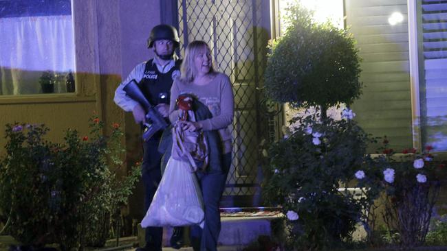 A police officer escorts a woman from a home ... in Redlands. Picture: AP