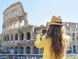 Woman taking photo of colosseum in rome, italy. rear view