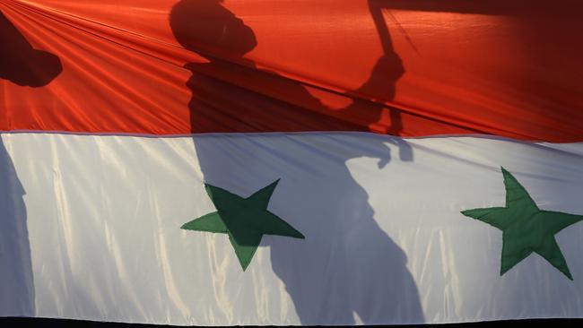 A protester holds a banner behind a Syrian flag outside the US embassy in Athens on Friday during a rally against any Western military intervention in Syria.