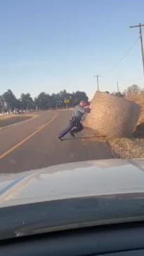 Cop who 'doesn't miss leg day' hauls hay bale off road   