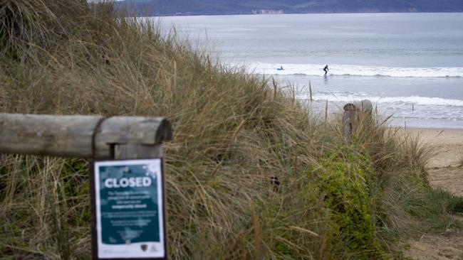 People surfing at Clifton Beach despite signs advising that Parks and Wildlife has closed the beach due to COVID-19. Picture: LUKE BOWDEN