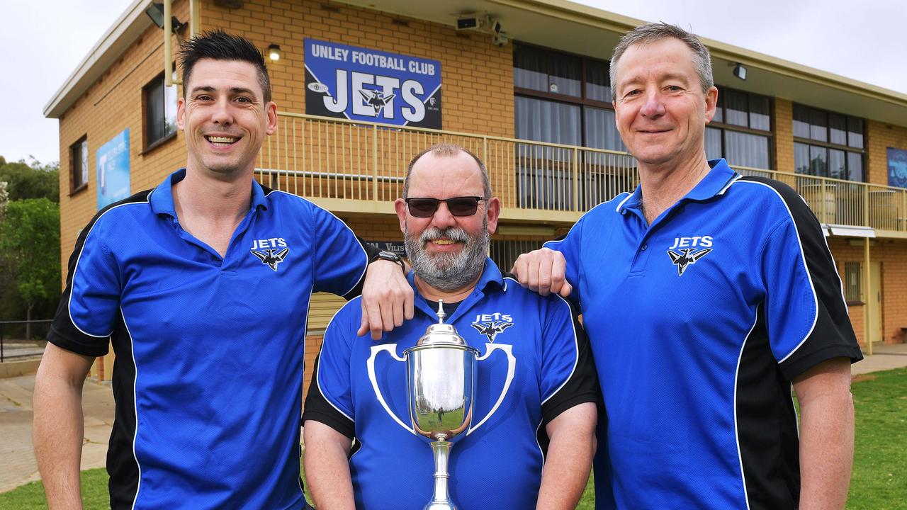 Unless Mercedes Jets seniors coach Kane Stewart,Operations manager Jeremy Pickering and club president David Heaslip pose outside their clubrooms with the trophy for competitionÕs club championship.Sunday October 6,2019.(Image AAP/Mark Brake)