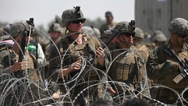 US soldiers stand guard behind barbed wire as Afghans sit on a roadside near the military part of the airport in Kabul hoping to flee from the country after the Taliban's takeover of Afghanistan. Picture: Wakil Kohsar/AFP