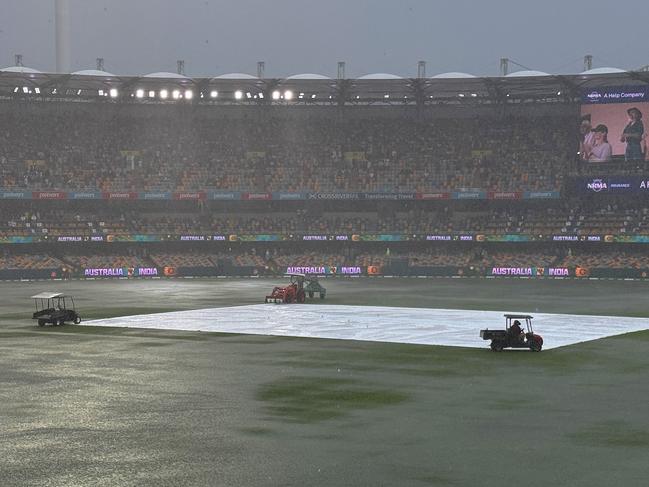 Heavy rain left a lake on the Gabba outfield as fans ducked for cover in the concourse areas. Picture: Getty Images